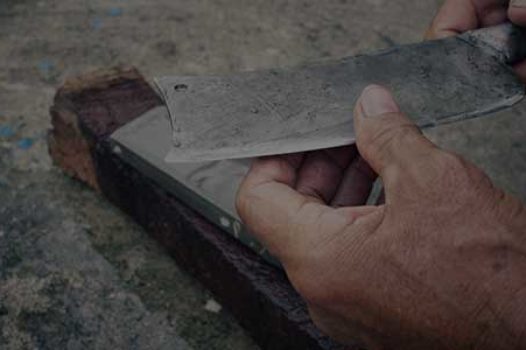 Man holding sharp recently sharpened knife above whetstone.